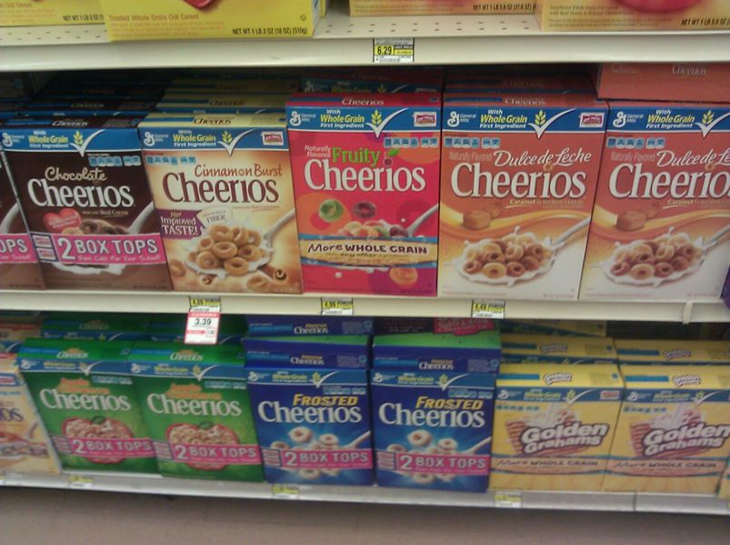 Shelf of Cheerios with lots of sugary flavors.