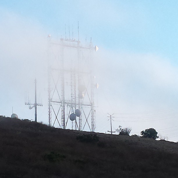 #fog rolling in over a hilltop transmission tower