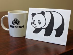 Paper panda next to an INITECH coffee mug.