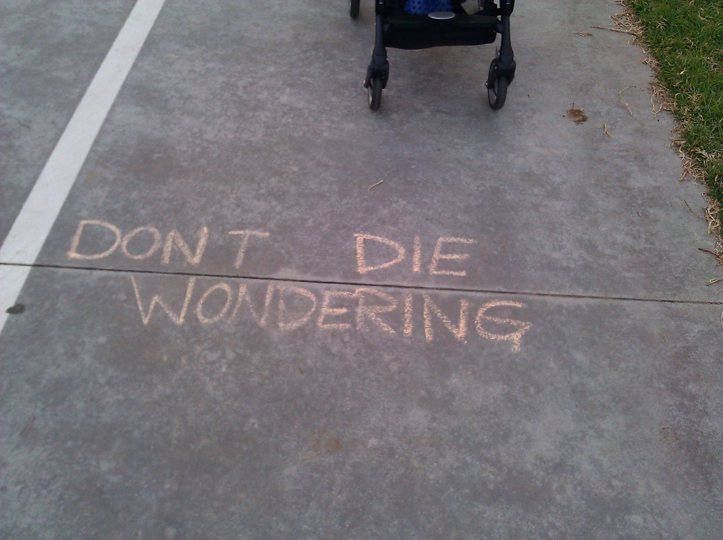 Written in chalk on a bike path: Don't Die Wondering.